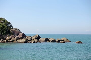 SEascape in Guaruja seashore, Brazil. Large rocks over blue sea water, calm no waves, clear horizon line