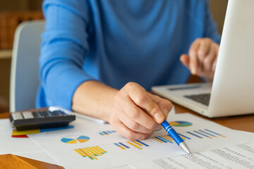 Businesswoman analyzing financial charts while using a laptop, developing an effective investment...