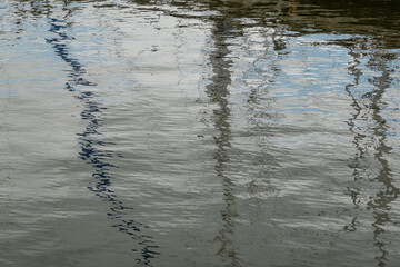 Reflections of boat masts creating abstract patterns on water surface