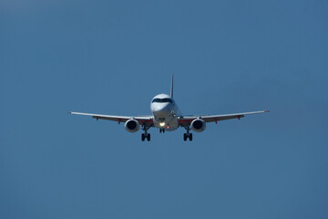 The plane approaching the airport. The plane is preparing to land. Airplane in the blue sky.