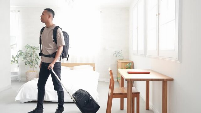 ホテルの部屋にスーツケースを持って立つ黒人男性旅行者