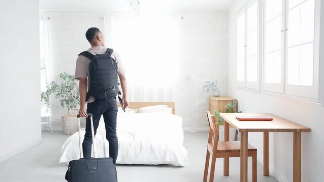 Black male traveler standing with suitcase in hotel room