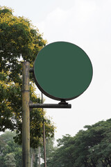 Blank round green sign on a pole, outdoor mockup. An empty circular signboard in a park with a...