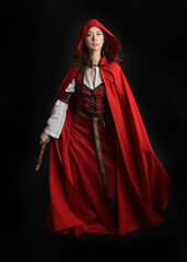 dramatic portrait of pretty young female brunette  model wearing a red hooded fairytale cloak and...
