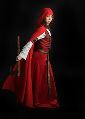 dramatic portrait of pretty young female brunette  model wearing a red hooded fairytale cloak and...