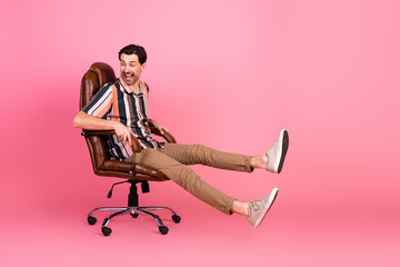Fashionable man enjoying leisure in a stylish chair against a vibrant pink background showcasing...