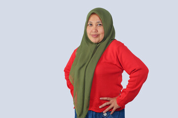 Confident Muslim woman standing with hands on waist in studio pose, ideal for concepts of strength,...