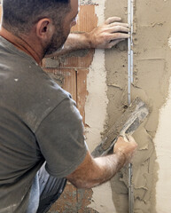 Craftsman uses a float trowel and cement to plaster a house wall. Construction process