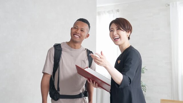 黒人男性旅行客に部屋を案内する女性ホテルスタッフ