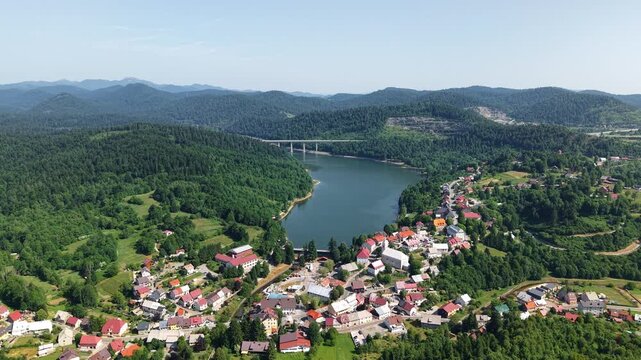aerial view of the town center of Fužine, Croatia. Colorful rooftops, curving streets, and parking areas create a dynamic urban pattern surrounded by greenery and water