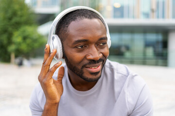 Music song concept. Good start day. Happy African American man listening modern hit on street in city. Person guy wearing headphones enjoy listening favorite music outdoor. People lifestyle joy