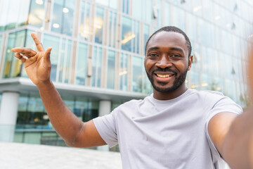 African American man with smartphone having video call on street in city. Guy blogger streaming...