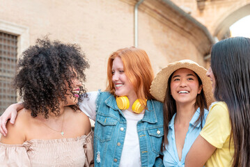 Multiracial female friends hugging and enjoying summer holidays in a european city
