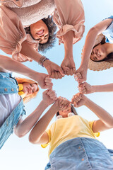 Low angle of Group of Happy multiracial female friends joining their hands in a circle