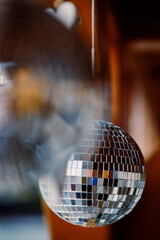 Mirrored disco balls are suspended on strings from wooden roof of beach bar