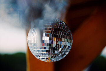 Mirrored disco balls are suspended on strings from wooden roof of beach bar