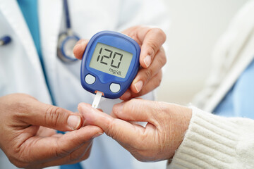 Asian doctor using digital glucose meter for check sample blood sugar level to treatment diabetes.