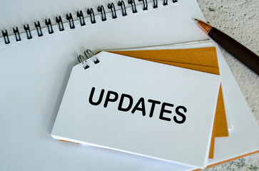 Top view of Updates text on white notepad. Business update concept.