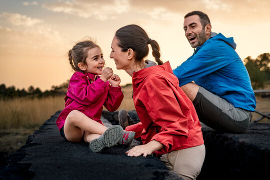 A mother and daughter share a joyful, laughing moment of connection outdoors at sunset. A happy family enjoying a tender moment of bonding and love during a hiking adventure.