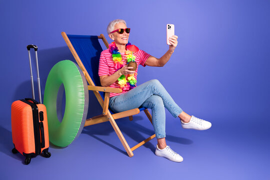 Elderly woman enjoying vacation spirit with tropical props, dressed in casual summer attire, showcasing leisure and lifestyle.
