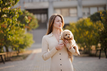 Stylish Woman Holding Cute Small Dog Outdoors in Park Animal Care and Companionship Concept
