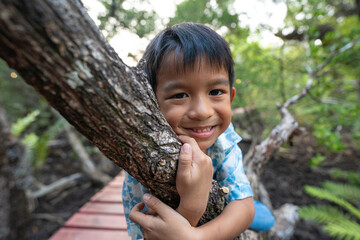Happy little boy enjoy travel in mangrove forest wooden walk way outdoor