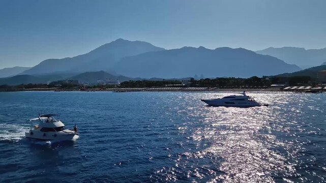 Seaside view to Kiris resort near Kemer, Turkey, with boats cruising on the deep blue Mediterranean Sea. Majestic Taurus mountain on the coastline background