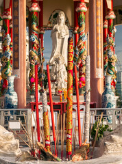 Large statue of Guanyin in colorful temple with dragon columns during sunny afternoon. Sriracha,...