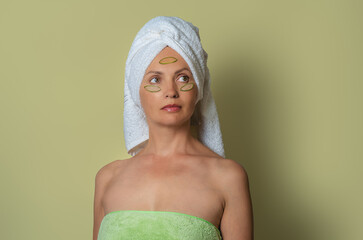 Cute woman on mustard background, in white towel and with bare shoulders. Relaxation, after shower.
