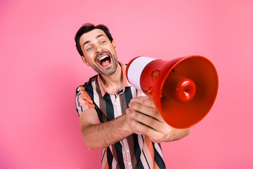Young man with megaphone on pink background promoting energetic positivity and enthusiasm, dressed...