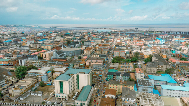 Aerial view of sprawling buildings and the Third Mainland Bridge stretching across the water, bathed in the soft light of day, Ikeja, Lagos, Nigeria.