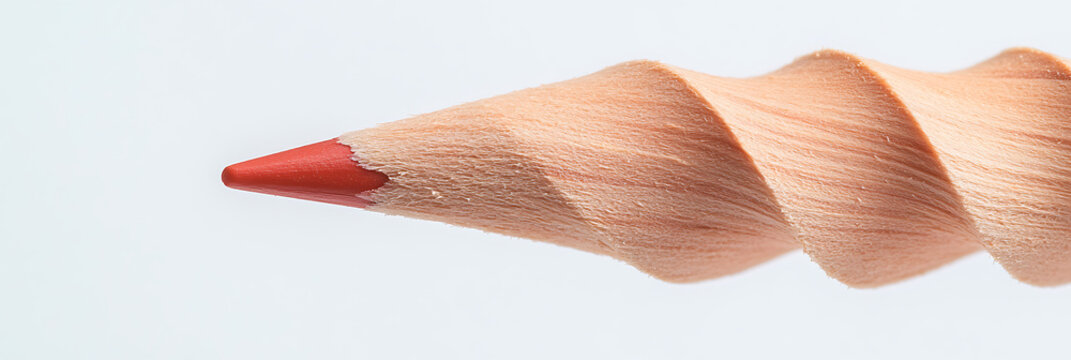 Close-up of a red colored pencil with a sharpened tip and wooden barrel showing a spiral pattern, set against a plain white background.