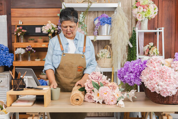 Asian senior woman, florist, small business owner, entrepreneur arranges flowers with passion at shop, showing creative occupation, independent lifestyle, customer service, retirement, aging society