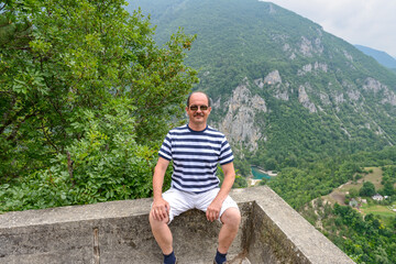 Portrait of man that is sitting on canyon background, Montenegro.