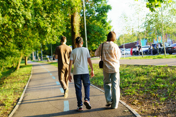 Obraz premium Family enjoys a leisurely walk on a sunny afternoon in a park surrounded by greenery