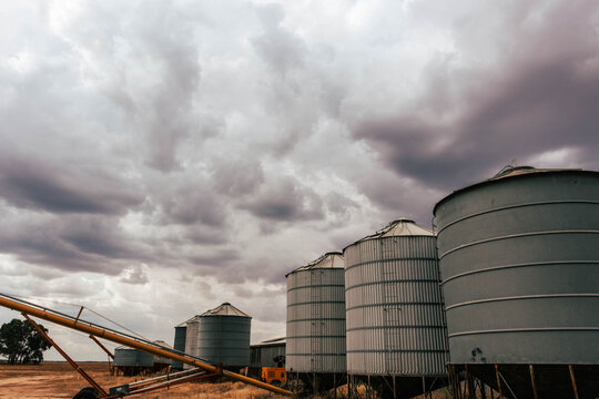 Silos standing in farm paddock as storm rolls in