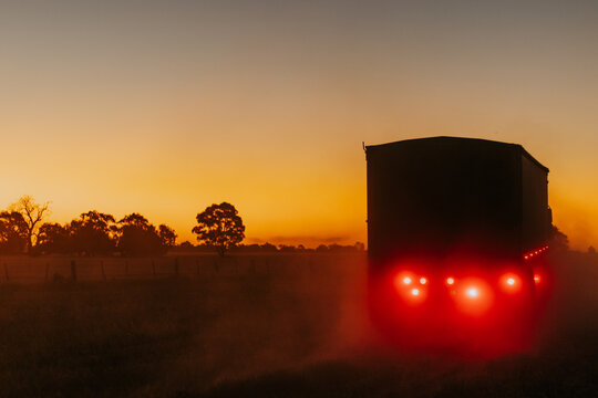 Truck driving into dusty sunset