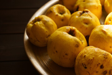 Quince fruits arranged beautifully on a ceramic plate in low light showcasing their natural texture and color