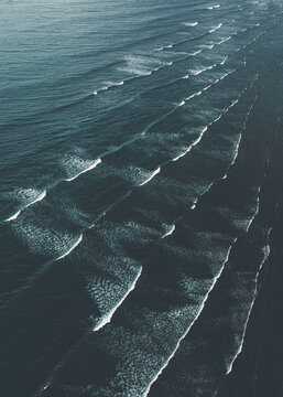 Aerial view of rhythmic waves crashing onto the sandy shore, creating a mesmerizing pattern of turquoise and white, Gold Coast, Queensland, Australia.