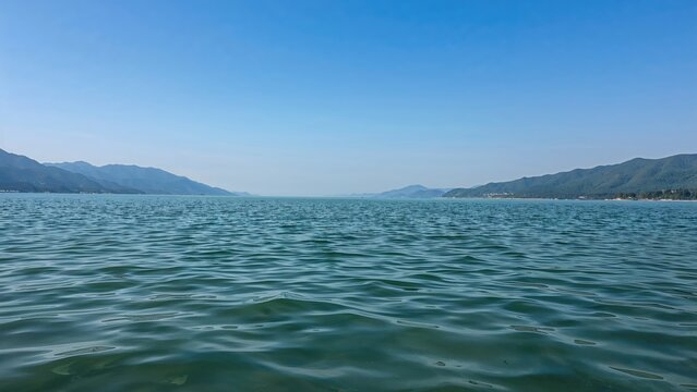 Vista across peaceful waters to remote foggy blue hills