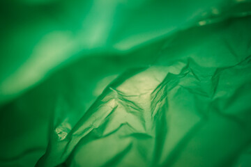Extreme close up of green empty plastic bag background. The plastic surface is wrinkly and tattered...
