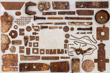 A group of various old rusty bits and pieces arranged on a concrete surface. Old rusty nuts, bolts, nails and other parts flay lay on gray background.