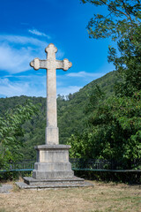 Une croix imposante en pierre, avec le roc de Courroux en arrière-plan