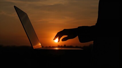 At dusk, a female silhouette gently closes a laptop, blending technology with nature.