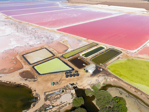 Aerial view of colourful salt evaporation ponds and levee banks at a coastal salt farm