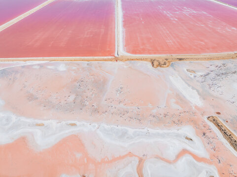 Aerial view of colourful salt evaporation ponds and levee banks at a coastal salt farm