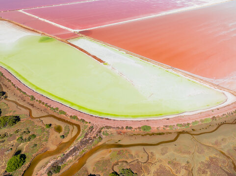 Aerial view of colourful salt evaporation ponds and levee banks at a coastal salt farm