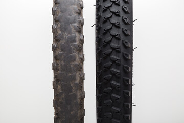 New and old bicycle tire tread on light gray background. Closeup. Compare two objects. Front view.