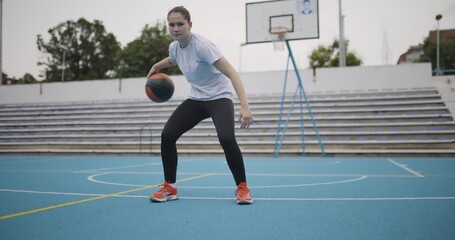 Confident female basketball player practicing dribbling skills on an outdoor court with focus and determination - Powered by Adobe