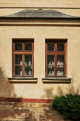 The two windows on the building are old and have wooden frames